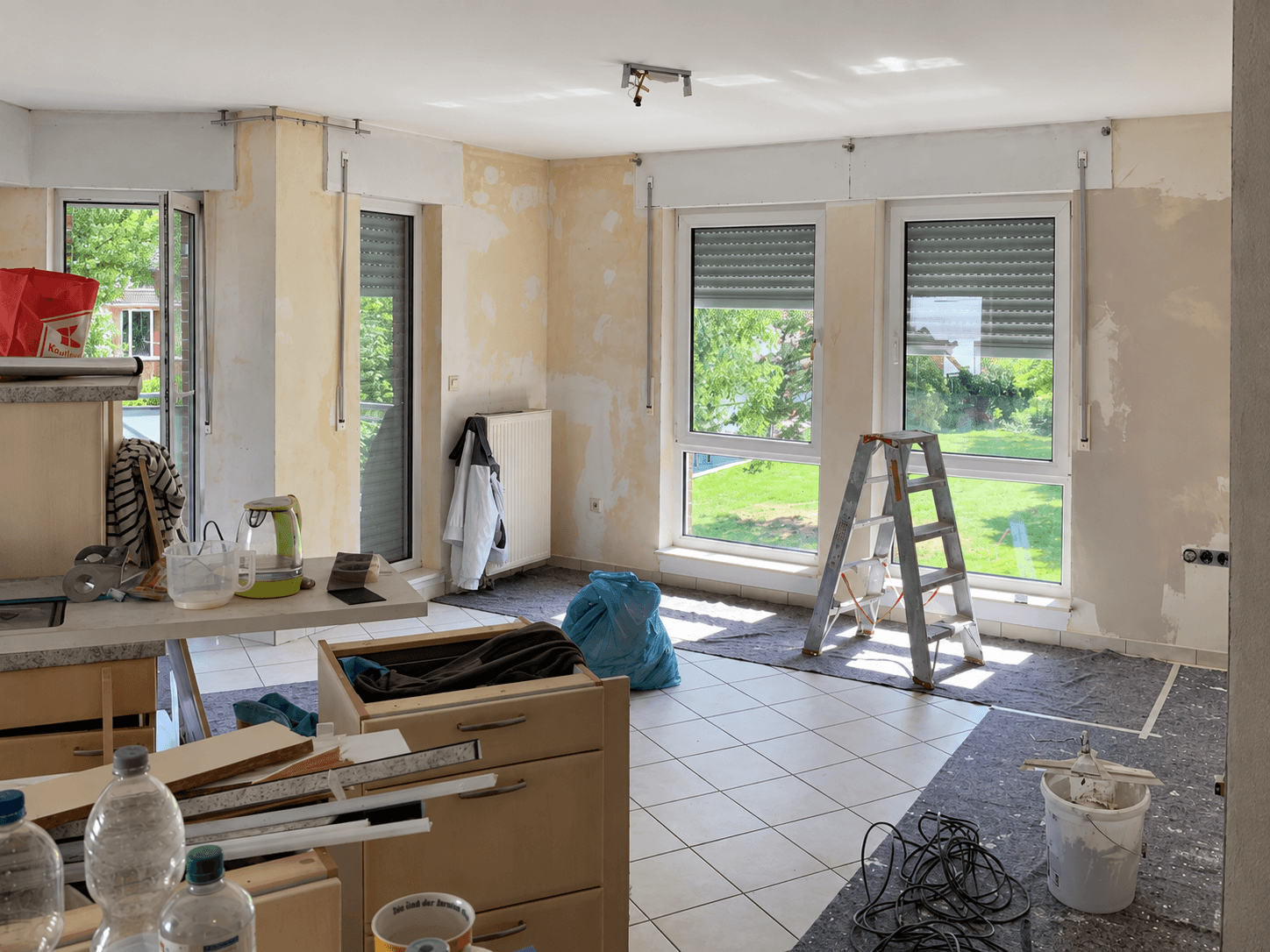 Wohnbereich während der Renovierung mit abgekratzter Tapete und Malerabdeckung